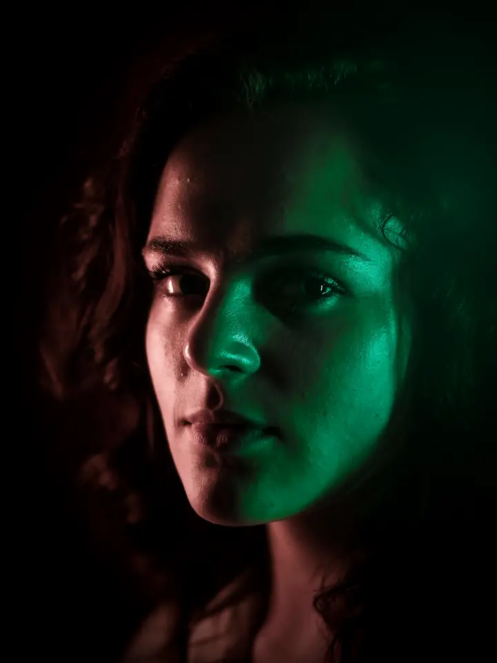 A woman lit by soft green light against a dark background