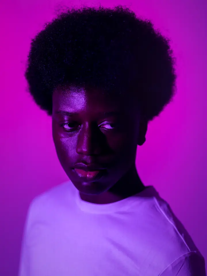 A man in a white shirt against a vivid violet backdrop