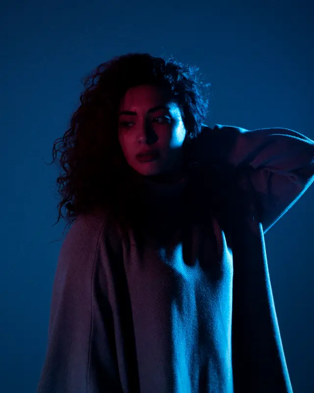 A woman with curly hair in a deep blue studio light
