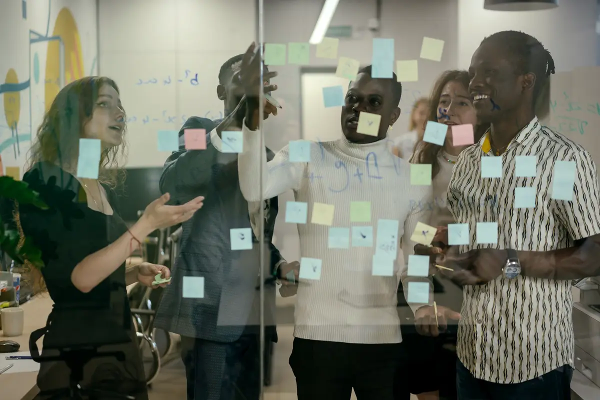 Colleagues mapping ideas with sticky notes on a glass wall